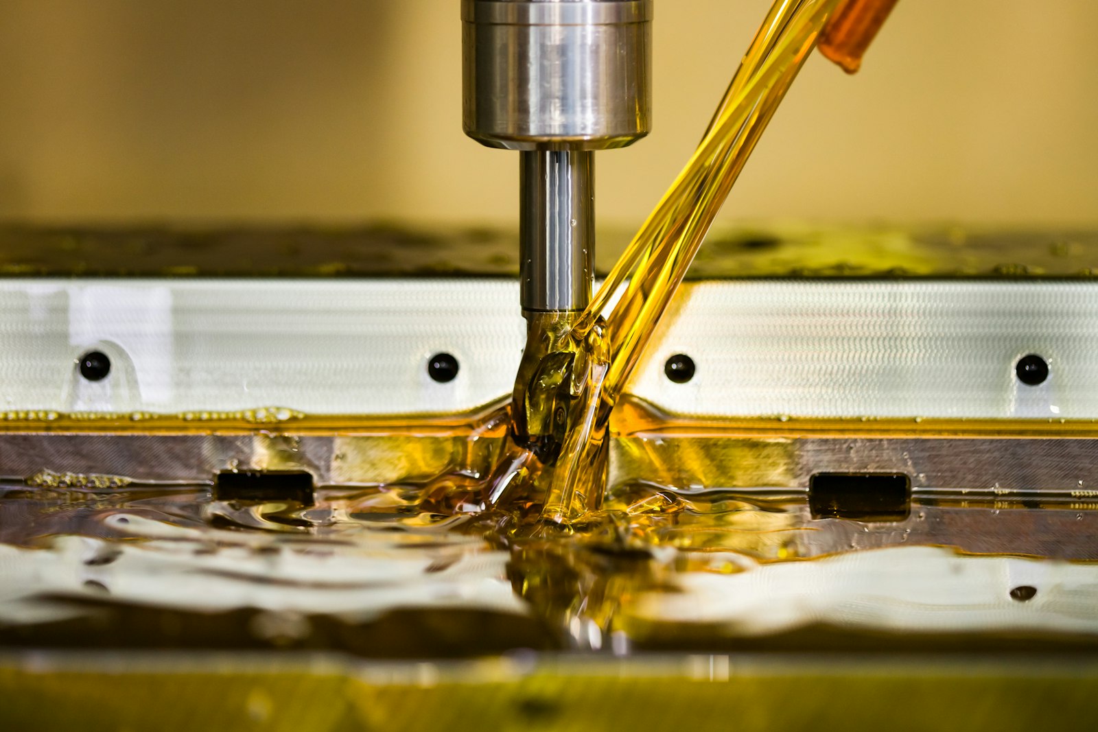 A CNC cutting tool machining a metal workpiece under a stream of cutting fluid