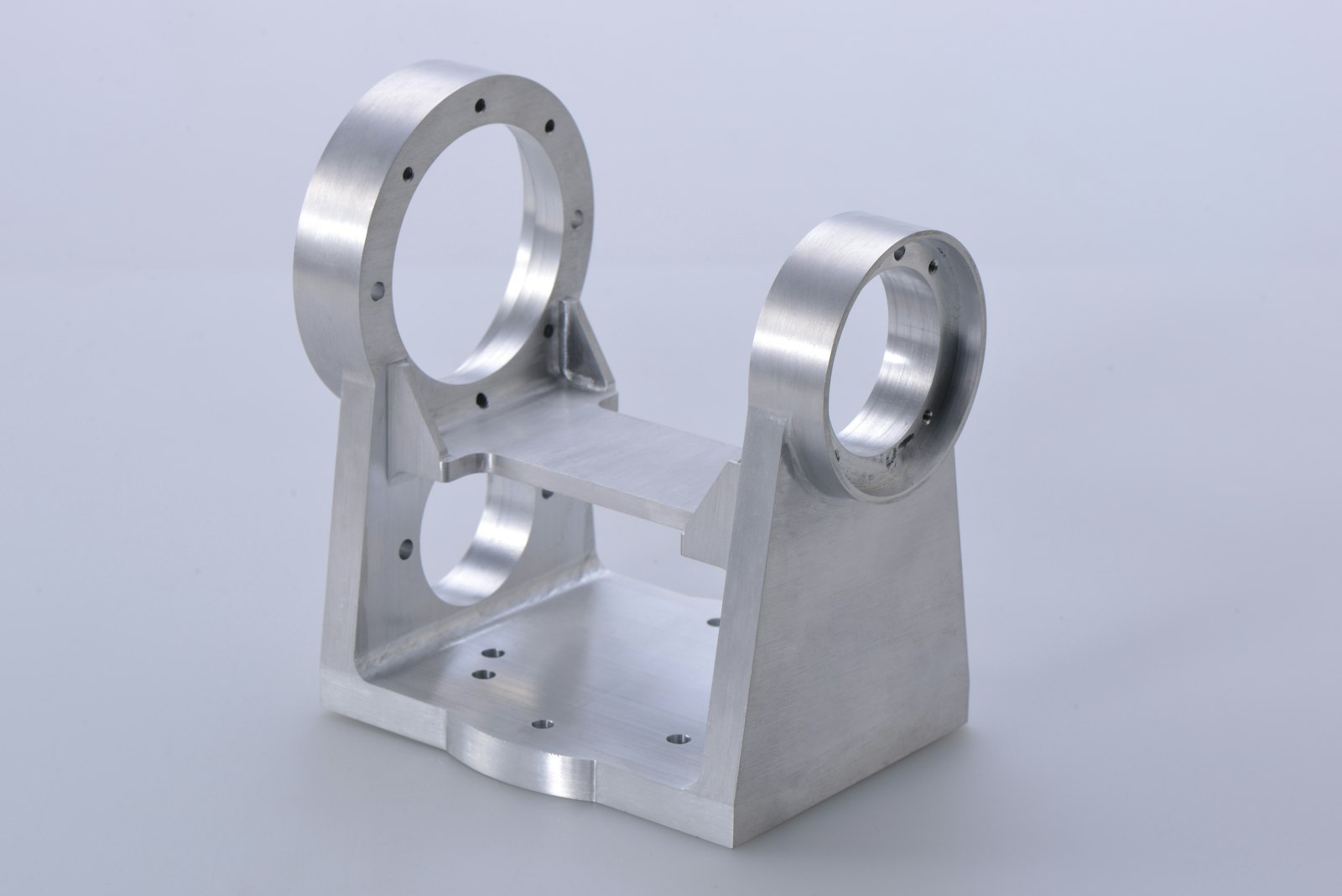 A precision-machined aluminum component with mirror-finished bores on a clean studio background